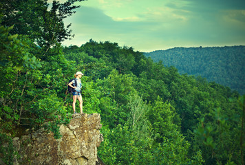 woman tourist with a backpack on a mountain top on a rock on the