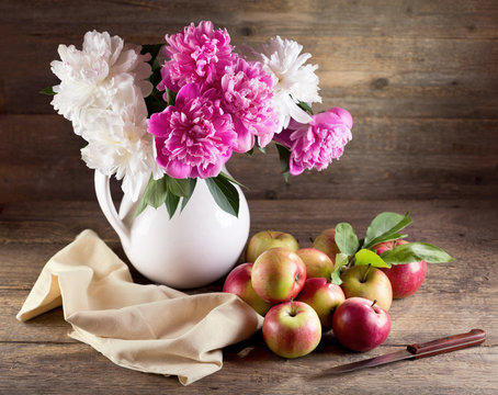 bouquet of peonies and red apples