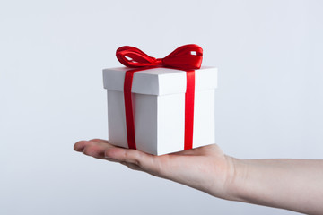 white gift box with red ribbon in hand