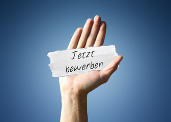 Man holding a scrap of paper with - Jetzt bewerben