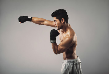 Young man practicing shadowboxing on grey background