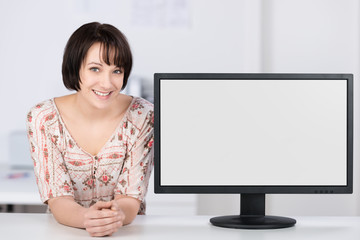 lächelnde frau neben pc-monitor