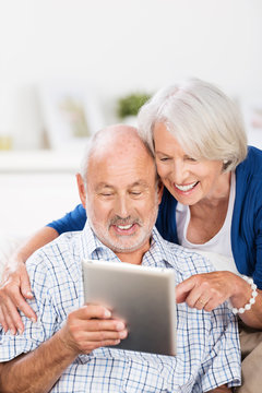 lachendes älteres paar schaut auf tablet-pc