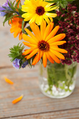 Bouquet of autumn flowers in vase on wooden background