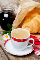 Cup of coffee and croissants on wooden background