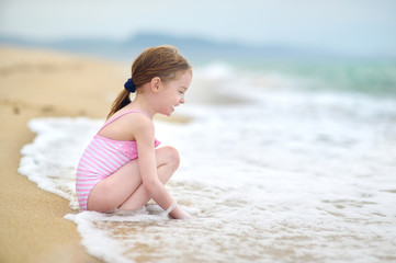 Fototapeta na wymiar Cute little girl playing on a beach