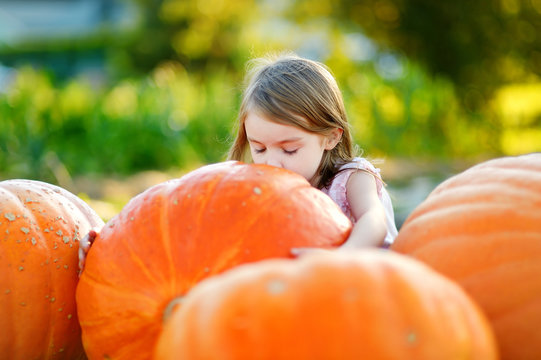 Adorable little girl embracing big pumpkin