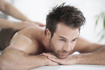 Handsome man laying on a massage bed