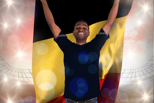 Composite image of excited football fan in black cheering holdin