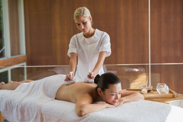 Fototapeta na wymiar Content brunette enjoying a herbal compress massage