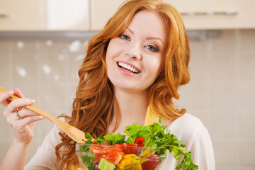 Smiling happy woman in the kitchen with salad
