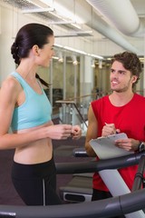 Fototapeta na wymiar Trainer talking to his client on the treadmill