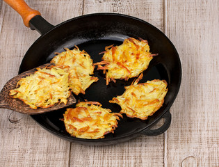 Golden potato fritters on old cast iron frying pan