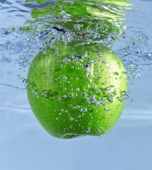 Zielone jabłko wpadające do wody - obrazy, fototapety, plakaty