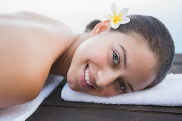 Obraz na płótnie Canvas Peaceful brunette lying on towel smiling at camera
