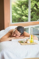 Obraz na płótnie Canvas Brunette lying on massage table with tray of beauty treatments