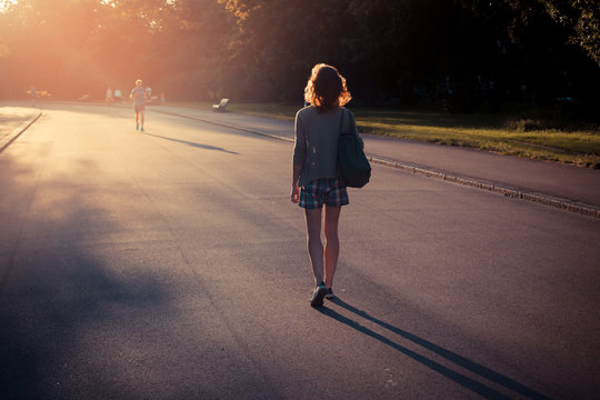 Woman walking into sunset in a park
