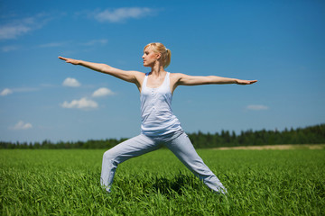 Beautiful woman practicing yoga on field. Yoga concept.