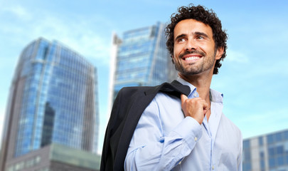 Smiling businessman holding his jacket outdoor