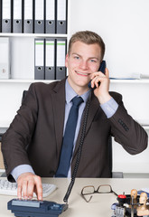 Junger Mann wählt eine Nummer am Telefon