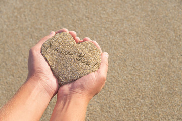 Hands holding a sand in form of the heart with text 