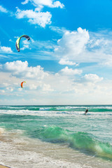 Kitesurfing. Kitesurfers rides the waves against sky.