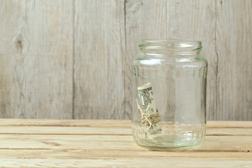 Money in glass jar on wooden table