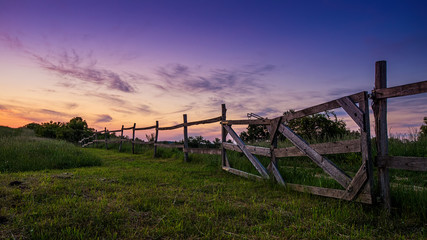 Fototapeta na wymiar Blue-colored twilight, old wooden fence in the foreground
