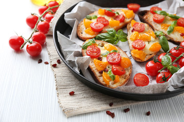 Obraz na płótnie Canvas Tasty bruschetta with tomatoes in pan, on table