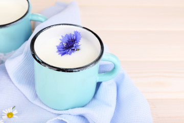 Cups of milk and cornflowers on wooden table