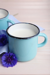 Cups of milk and cornflowers on wooden table