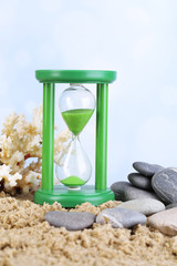 Hourglass in sand on bright background