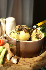 Young boiled potatoes in pan with vegetables on table in