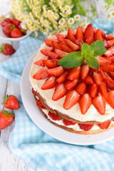 Delicious biscuit cake with strawberries on table close-up