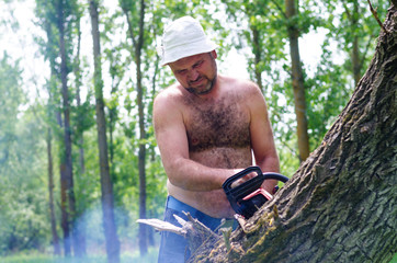 Fit man carrying a chainsaw in woodland