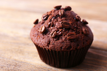 Chocolate muffin and coffee grains on wooden background