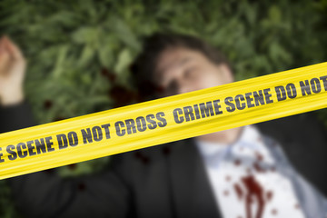 Yellow crime scene cordon tape over a  body of a man