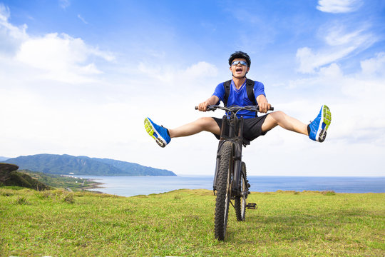 funny young backpacker riding a bicycle on a meadow