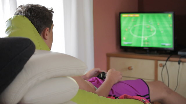 Teen playing with game at home (back view)