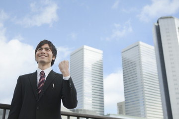 ビルの前でガッツポーズをするビジネスマン