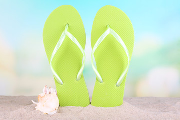 Bright flip-flops on sand, on nature background