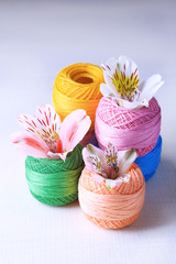 Colorful clews and fresh flowers on light background