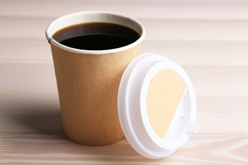 Paper cup of coffee on wooden table