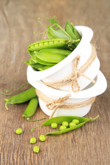 Fresh green peas in bowl on wooden table