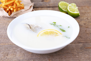 Tasty soup with oysters on wooden table