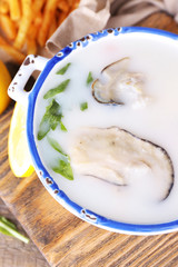 Tasty soup with oysters on wooden table