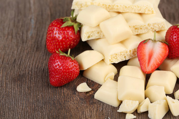 Broken white chocolate bar with fresh strawberries,