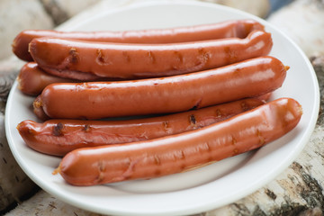 Glass plate with grilled sausages, horizontal shot, close-up