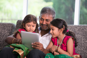indian father with his daughter using a tablet computer on livin