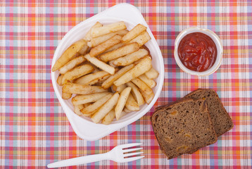 Fried potatoes in a plate on a tablecloth.